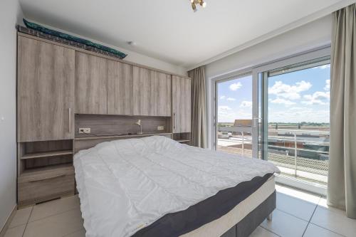 a bedroom with a large bed and a large window at Volledig gerenoveerd 2 slaapkamer appartement in Westende-Bad, 250 m van het strand in Westende Bad