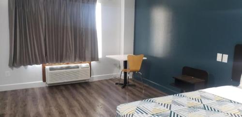 a room with a bed and a desk and a table at Studio 6 Suites Hesperia, CA West Main Street I 15 in Hesperia