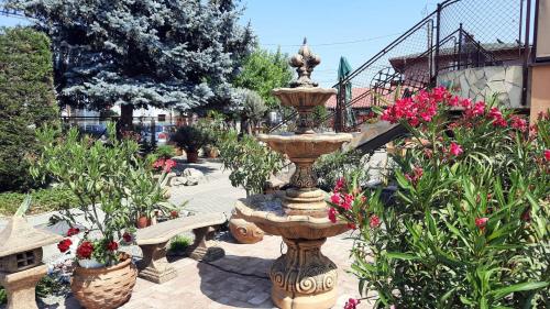 a fountain in the middle of a garden with flowers at Sarokhaz Panzio in Vecsés