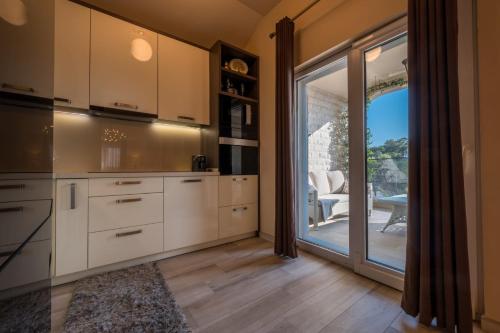 een keuken met witte kasten en een glazen schuifdeur bij Apartmani Tip-Top in Tivat