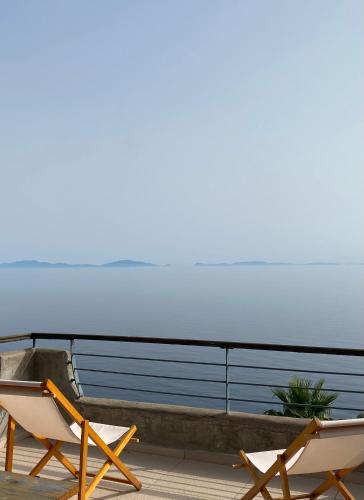 two chairs on a deck with the ocean in the background at Frictories station of residency in Limniónas