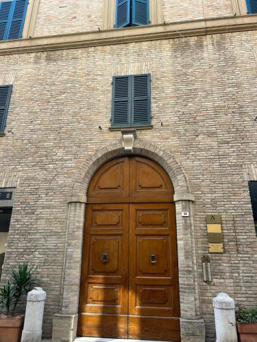 eine große Holztür an einem Backsteingebäude in der Unterkunft Montevecchio 56 in Fano