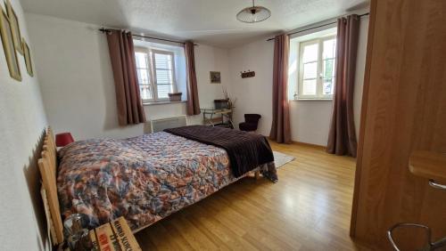 a bedroom with a bed and two windows at Appartement Melou rez de chaussée in Gérardmer