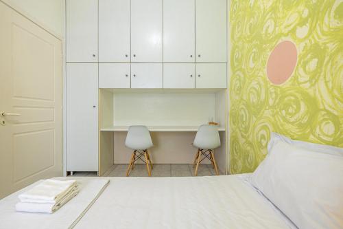a bedroom with a bed with white cabinets and two chairs at The Libyan Coast House in Paránimfoi