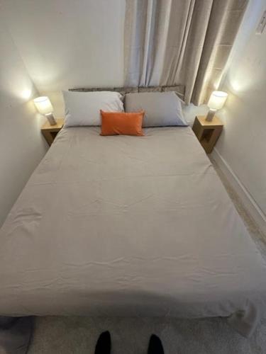 a bed with two pillows and an orange pillow on it at Castle Walk Apartment in Stirling