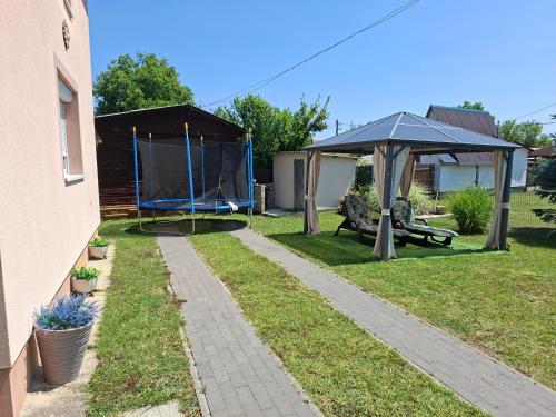 a backyard with an umbrella and a table and a bench at Levendula Vendégház in Hajdúnánás