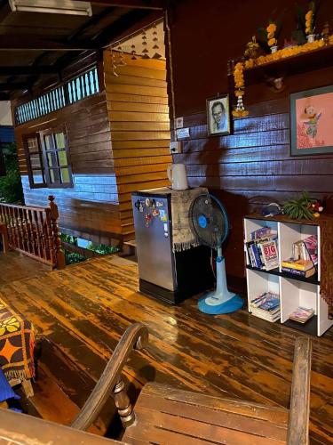a room with a wooden floor with a refrigerator at Banthai Guesthouse in Phetchaburi
