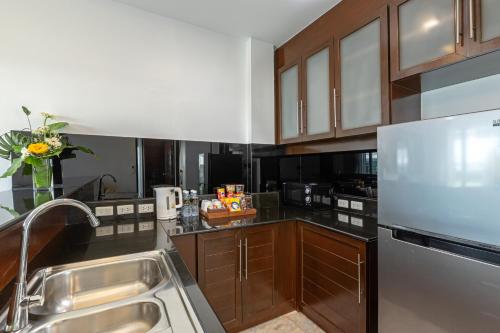 a kitchen with a sink and a stainless steel refrigerator at Phunawa Resort Phuket Karon Beach - SHA Plus in Karon Beach