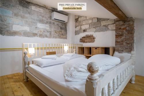 a white bed in a room with a brick wall at Garage Apartments in Nova Gorica