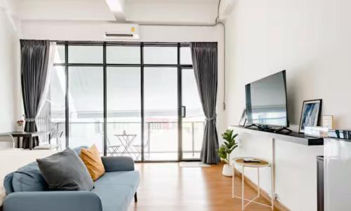 a living room with a blue couch and a large window at Homemade Ice cream house in local village in Bangkok