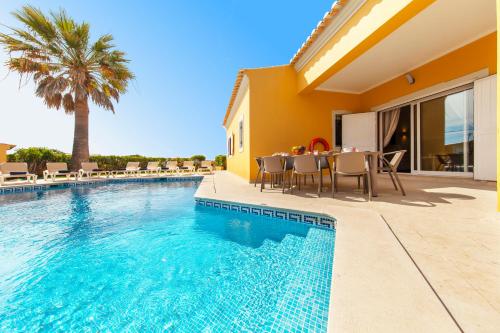 a villa with a swimming pool with a table and chairs at Villa Palms by Algarve Vacation in Albufeira