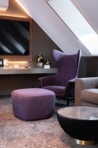 a living room with a purple chair and a tv at Riva Prestige Hotel in Szeged