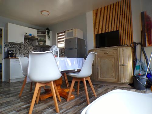 a kitchen with a table and four white chairs at La Villa d'Elisa in Saint-Côme-de-Fresné