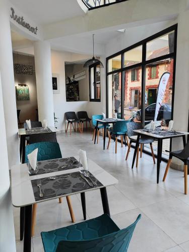 a dining room with tables and chairs and windows at HOTEL HI Fianarantsoa in Mandriankeniheny