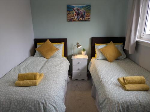 a bedroom with two beds with yellow pillows at Edinburgh Home from Home in EDI