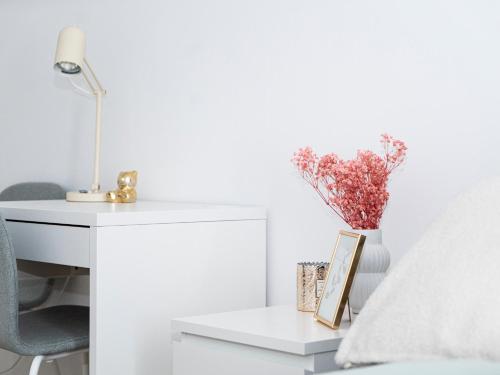 a white desk with a vase of flowers next to a chair at Lottes Hus in Lübeck