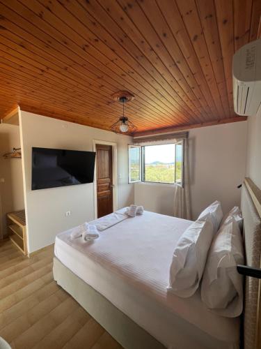 a bedroom with a large bed with a flat screen tv at Niriton Pension in Nydri