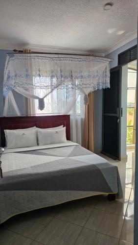 a bedroom with a bed with a canopy and a window at Occazia Hotel in Mbarara