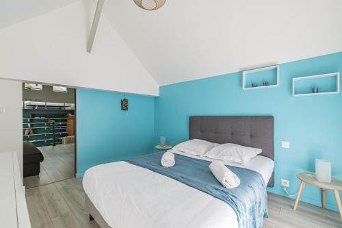 - une chambre bleue avec un grand lit et des oreillers blancs dans l'établissement Au coeur du village Verzenay, à Verzenay