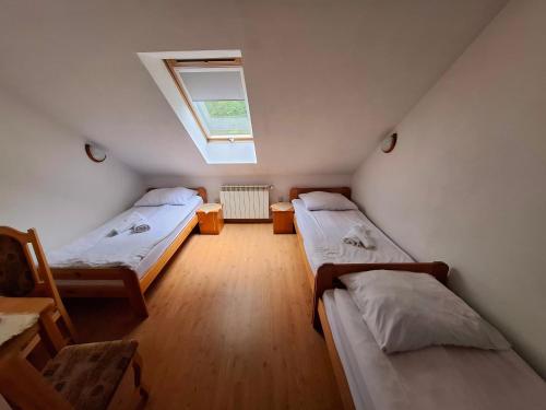 a attic room with two beds and a window at Zajazd Gajówka in Zwierzyniec