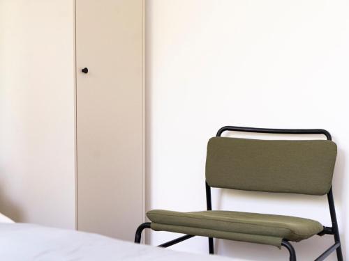 a green chair sitting next to a bed at Lottes Hus in Lübeck