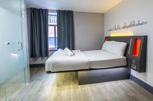 a bedroom with a bed and a glass shower at easyHotel Leeds in Leeds