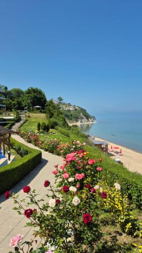 Un jardín con flores rojas y blancas junto a una playa. en White Cliffs первая линия, en Byala