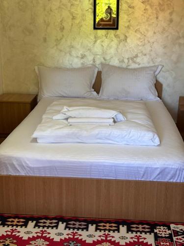 a bed with white sheets and pillows on it at Pensiunea Anca Sapanta-primeste carduri de vacanta in Săpînţa