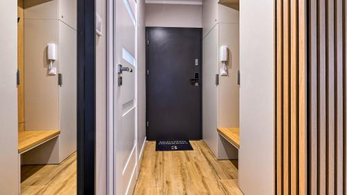 a hallway with a black door and wooden floors at Centrum Park II, Sun & Snow in Szklarska Poręba