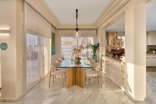 a dining room with a glass table and chairs at The Sea View Penthouse Ashdod in Ashdod