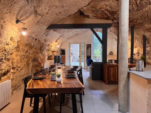 a dining room with a long wooden table with chairs at Evasion Troglodyte insolite spa et nature in Doué-la-Fontaine