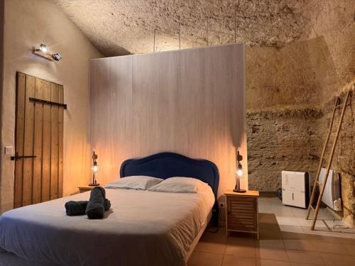a bedroom with a bed with a blue head board at Evasion Troglodyte insolite spa et nature in Doué-la-Fontaine