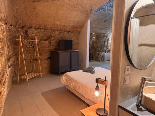 a bedroom with a bed and a mirror in a cave at Evasion Troglodyte insolite spa et nature in Doué-la-Fontaine