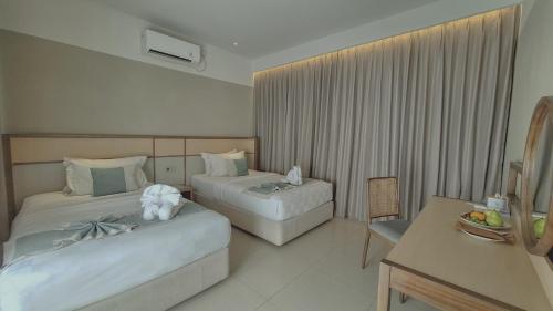 a hotel room with two beds and a table at The Allure Villas Managed by Sahid in Pangandaran