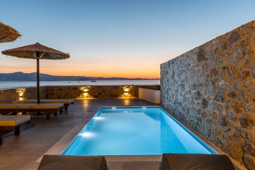 a pool with a stone wall and a villa at Lithia Exclusive Villas in Plaka