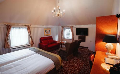 a hotel room with a bed and a red chair at Grand Museum Hotel, BW Signature Collection in Delft