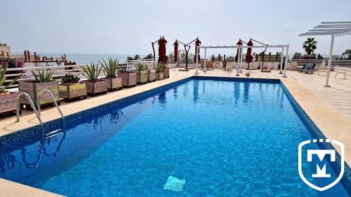 a swimming pool with chairs and the ocean in the background at Hotel La Residence Hammamet in Hammamet