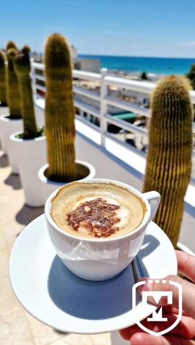 a cup of coffee on a plate next to cactus at Hotel La Residence Hammamet in Hammamet