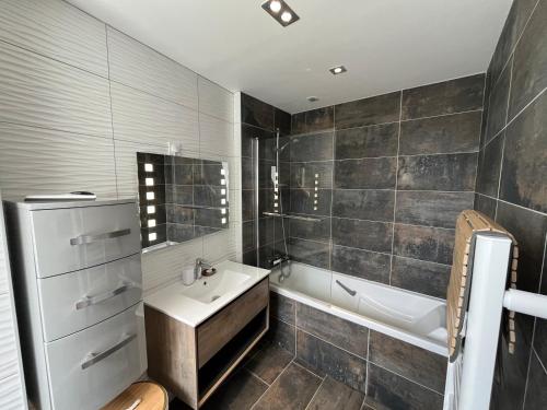 a bathroom with a white tub and a sink and a bath tubermott at La Perle de la Côte in Boulogne-sur-Mer