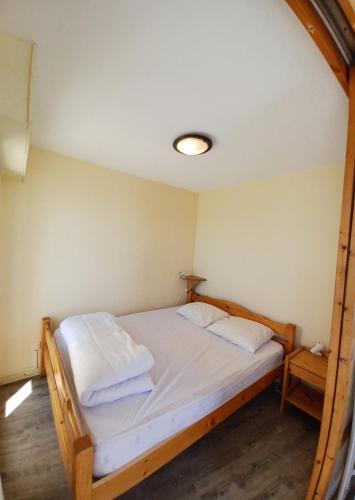 - une chambre dotée d'un lit avec des draps blancs dans l'établissement Le Sunset, à Mimizan