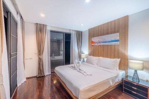 a bedroom with a large white bed and a window at 卡图精品五卧高尔夫场别墅 in Phuket Town
