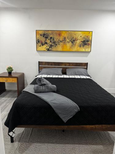 a bedroom with a black bed with a painting on the wall at Santuaria Hollywood in Hollywood