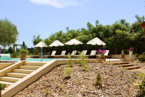 une piscine avec chaises et parasols dans une cour dans l'établissement Mas de l'Hermitage, à Moulès