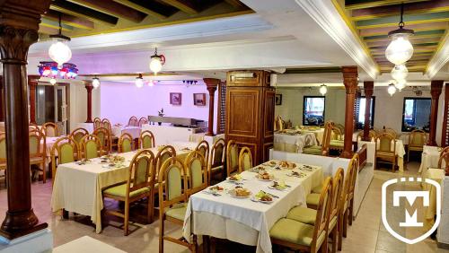 a restaurant with white tables and chairs and a pink wall at Hotel La Residence Hammamet in Hammamet