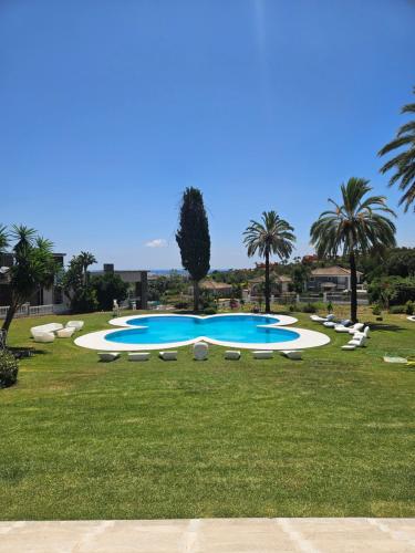 a large swimming pool with lounge chairs and palm trees at Palacio Suites Marbella in Marbella