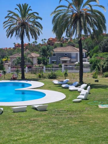 a pool with chairs and palm trees in a yard at Palacio Suites Marbella in Marbella