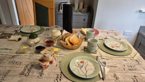a table with plates and a basket of food on it at Sheepviewhouse Jamie in Kilgarvan