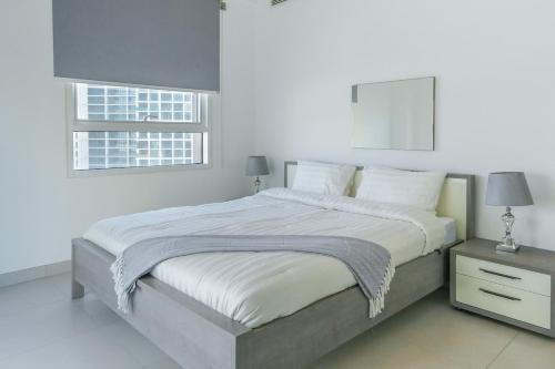 a white bedroom with a large bed and a window at Cozy 1br in Parkside A in Abu Dhabi