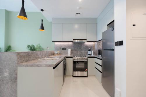 a kitchen with white cabinets and stainless steel appliances at KeyRock Golf Gate - Relax and Unwind with Pool and Sauna in Dubai