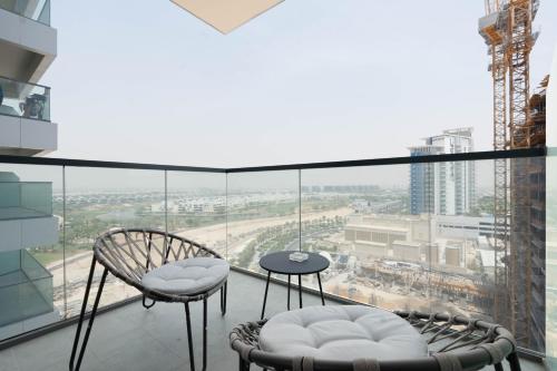 a balcony with two chairs and a table at KeyRock Golf Gate - Relax and Unwind with Pool and Sauna in Dubai